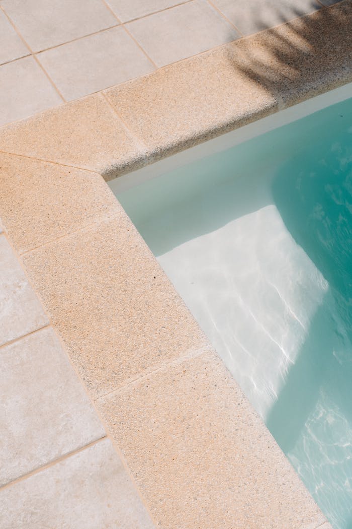 Serene close-up view of a swimming pool's edge with turquoise water in bright sunlight.